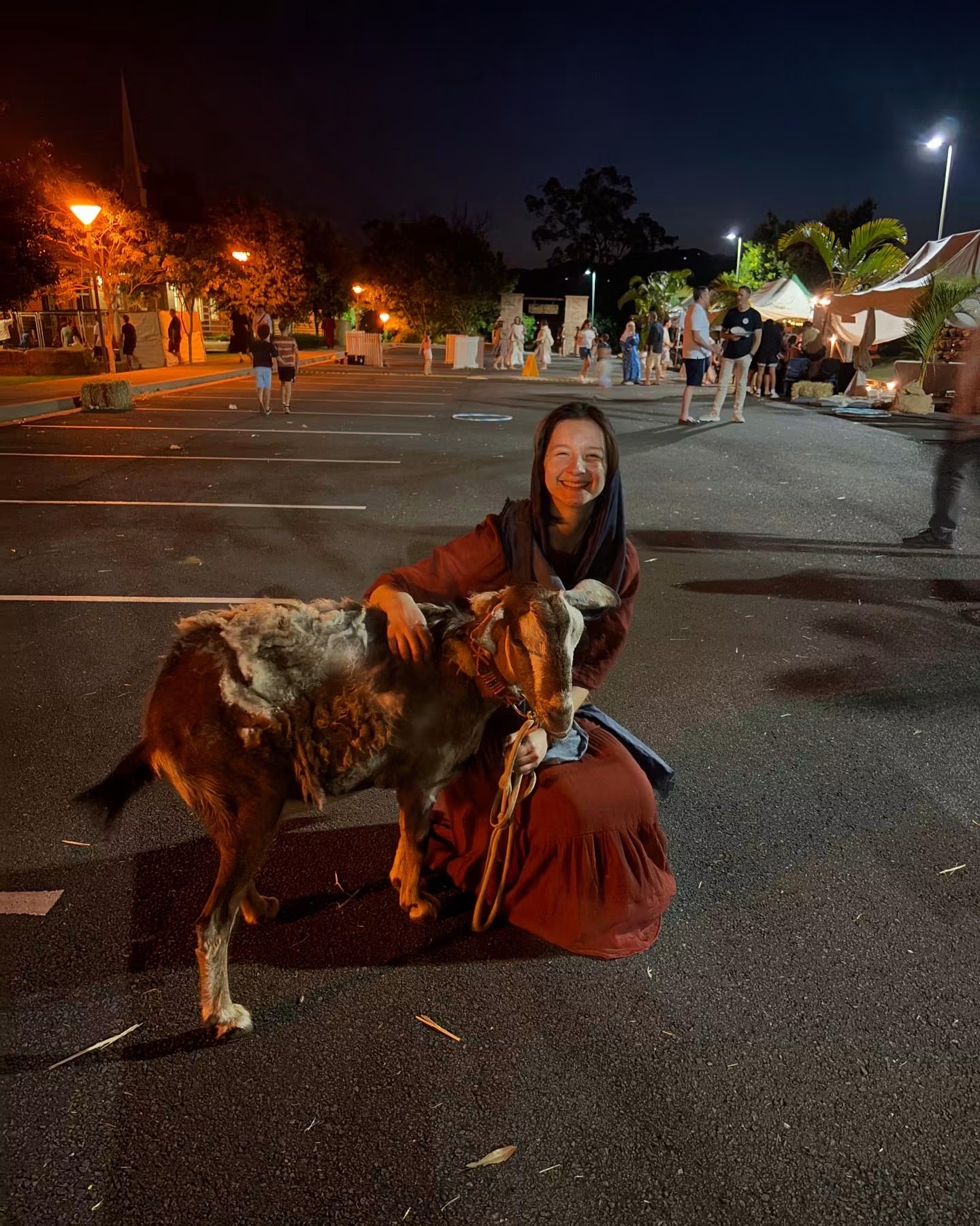 A villager leading a goat on a rope through the grounds after dark